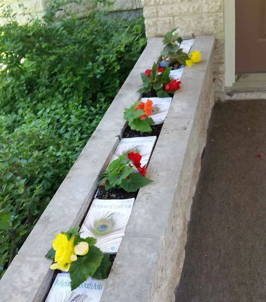 Books laid beneath plants as a weed barrier.